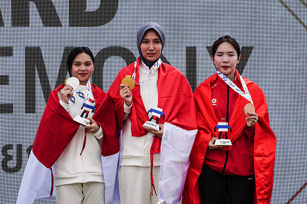 Mubarokah Dewi Laila of Indonesia, the gold medalist, celebrates on the podium during the medal ceremony with Karini Dominique Rachmawati of Indonesia, the silver medalist, and Phi Thanh Thao of Vietnam, the bronze medalist, at the women's 10m Air Rifle final at the 33rd Sea Games in SAT Shooting Range, Bangkok, Thailand, on December 13, 2025. (Photo by Anusak Laowilas/NurPhoto via Getty Images)