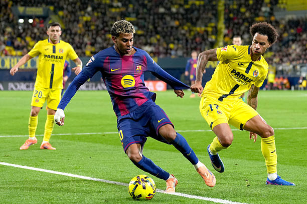 VILLARREAL, SPAIN - DECEMBER 21: Lamine Yamal of FC Barcelona is challenged by Tajon Buchanan of Villarreal CF during the LaLiga EA Sports match between Villarreal CF and FC Barcelona at Estadio de la Ceramica on December 21, 2025 in Villarreal, Spain. (Photo by Alex Caparros/Getty Images)